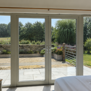 Bright bedroom with large glazed doors demonstrating how solar window film can reduce heat and glare while maintaining natural light and outside views.